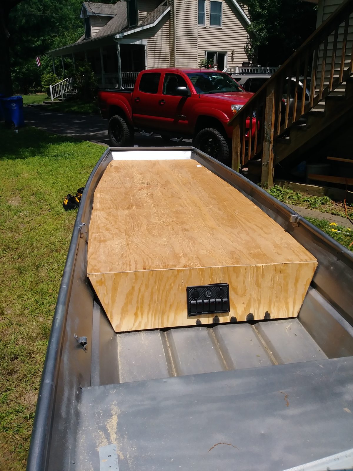 Plywood switch panel box test-fit inside the hull, house and truck in the driveway beyond